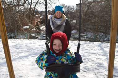 Çocuk kışın salıncak üzerinde