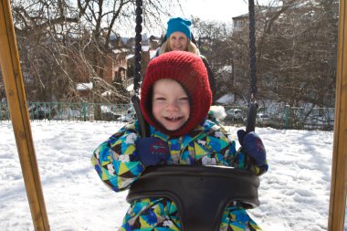 Çocuk kışın salıncak üzerinde