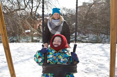 Çocuk kışın salıncak üzerinde