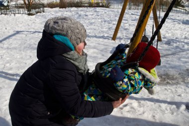 Çocuk kışın salıncak üzerinde