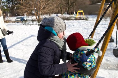 Çocuk kışın salıncak üzerinde