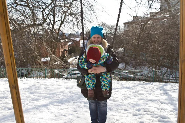 Ребёнок на качелях зимой — стоковое фото