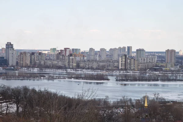 Kiev, 24 de março de 2018, Ucrânia. Vista da cidade e imobiliário através do rio de inverno no gelo — Fotografia de Stock