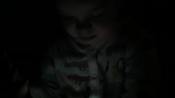 Jongen van twee jaar kijken cartoons op zijn tablet bij nacht — Stockvideo