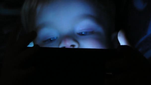 Niño de dos años viendo dibujos animados en su tableta por la noche — Vídeos de Stock