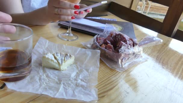 2018 キエフ フランス産チーズの頭と燻製肉のパッキング テーブル上にあります アルコールのガラスと男性と女性の手 グラスの中のアルコールのクローズ アップ — ストック動画