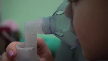 Üç yaşında bir çocuk oksijen maskesi soluyor. Solunum yolu solunumu. Maske astım spreyi.