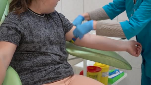 十代の女の子は分析のための血を与える 静脈からの血液採取ゴム手袋の手は静脈から血液検査を受ける — ストック動画