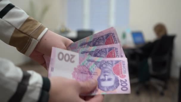 女人的手考虑乌克兰格里夫尼亚 乌克兰钱在一个办公室职员的背景下手里 办公室台式机背景下的乌克兰钱 — 图库视频影像