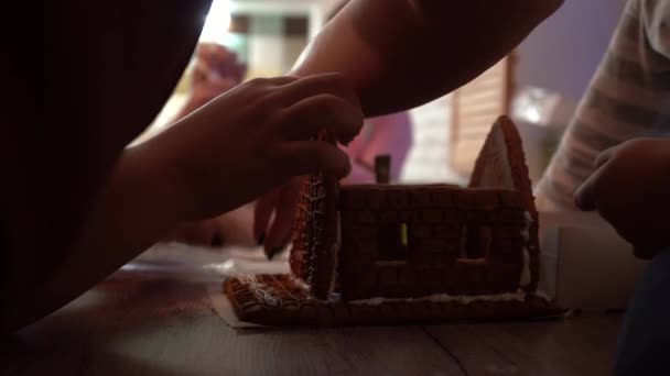 enfants avec les parents font des biscuits de pain d'épice de Noël. Pain d'épice de Noël sous la forme d'une maison. Les enfants collectionnent le pain d'épice avant Noël. Crème pour pain d'épice .