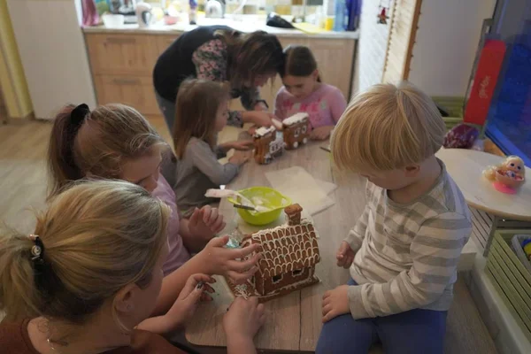 Kerst peperkoek in de vorm van een huis. Kinderen verzamelen peperkoek voor Kerstmis. Crème voor peperkoek. — Stockfoto