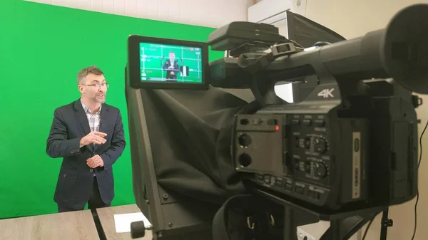 En bloggare spelar in en video på en grön bakgrund. Registrering a v — Stockfoto