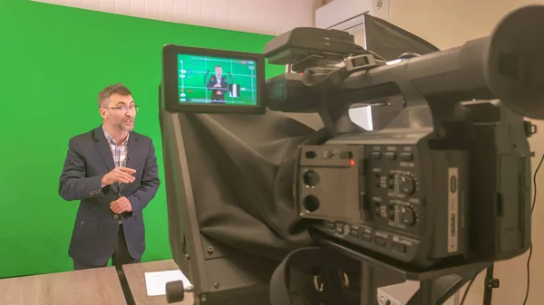 Bir blogcu yeşil arka planda bir video kaydediyor. Bir v kaydet