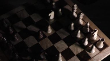 Shadows of chess in the dark. Chess board with pieces. Shadow of chess pieces on a dark background. Shadows of chess on a chessboard. Light illuminates chess pieces.