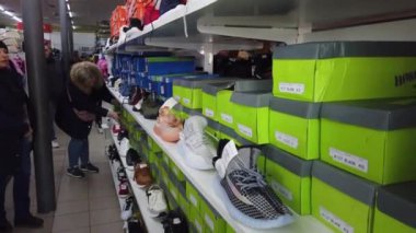 Europe, Kiev, Ukraine - February 2020: The buyer tries on sneakers in a shoe store. Shelves with shoes in a shoe store.