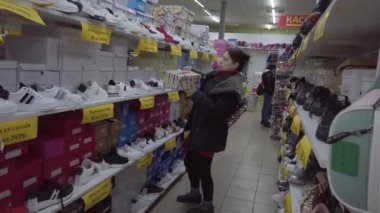 Europe, Kiev, Ukraine - February 2020: The buyer tries on sneakers in a shoe store. Shelves with shoes in a shoe store.