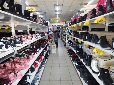 Europe, Kiev, Ukraine - February 2020: The buyer tries on sneakers in a shoe store. Shelves with shoes in a shoe store.