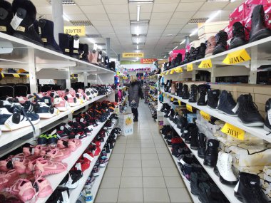 Europe, Kiev, Ukraine - February 2020: The buyer tries on sneakers in a shoe store. Shelves with shoes in a shoe store.