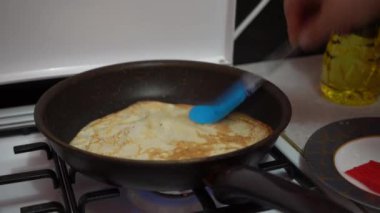 Europe, Kiev, Ukraine - March 2020: a girl bakes pancakes in a pan. Pan with pancake on a gas stove.