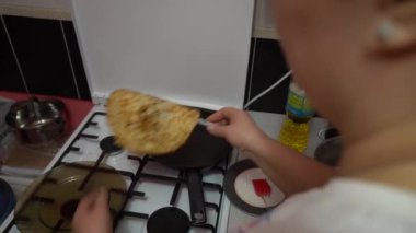 Europe, Kiev, Ukraine - March 2020: a girl bakes pancakes in a pan. Pan with pancake on a gas stove.