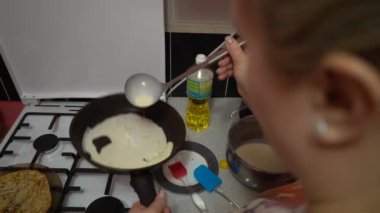 Europe, Kiev, Ukraine - March 2020: a girl bakes pancakes in a pan. Pan with pancake on a gas stove.