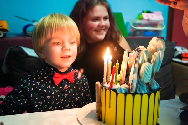 Four year old boy blew out candles in a cake. Birthday of a child of four years. Cake number 4. Family celebration of birth of a son.