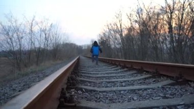 Dört yaşında bir çocuk demiryolu pistinde oynuyor. Sarı yolda bir çocuk raylarda oynuyor. Demiryolunda tehlike var..