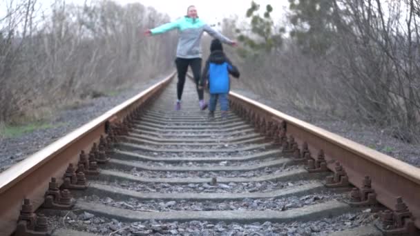 一个带着一个十几岁的女孩和一个孩子坐在铁路上 孩子们在铁路上玩耍 — 图库视频影像