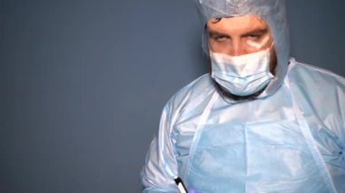 Koruyucu giysili sakallı bir doktor Covid-19 Coronavirus salgını sırasında laboratuvar şişelerini analiz için kontrol ediyor. Sisli maskeli yorgun doktor.