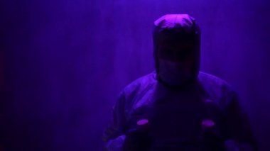 Koruyucu giysili sakallı bir doktor Covid-19 Coronavirus salgını sırasında laboratuvar şişelerini analiz için kontrol ediyor. Sisli maskeli yorgun doktor.