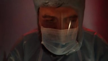 Laboratuvarda kırmızı-mavi acil durum ışığı olan koruyucu kıyafetli bir doktor. Koronavirüs salgını sırasında acil laboratuvar..