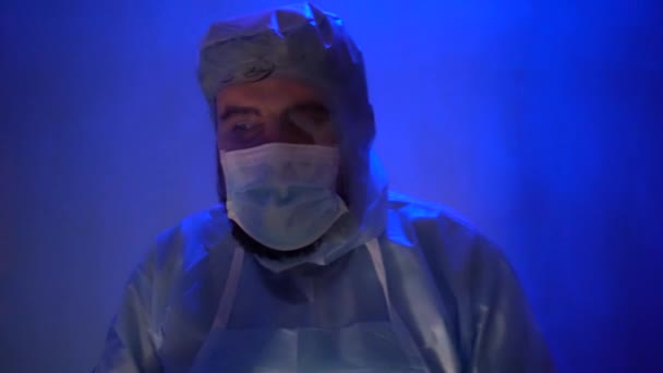 研究室での不安の間に保護医療訴訟でひげそりの医師 コロナウイルスパンデミックの間の研究室での事故 サイレンの光は青赤です 部屋の悪い照明の効果 — ストック動画