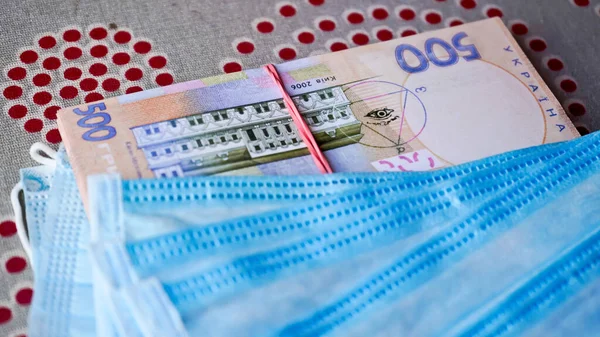 Medical masks with money. Ukrainian money with protective masks. A fan of Ukrainian hryvnia with a fan of medical masks.