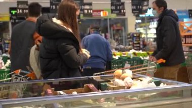 Avrupa, Kiev, Ukrayna - Nisan 2020: tıbbi maskeli bir alıcı ovid-19 koronavirüs salgını sırasında bir süpermarketten ürünler seçer (satın alır). 