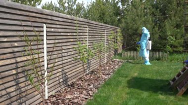 Koruyucu kabuklu biri özel bir kulübede Covid-19 'a karşı önlem olarak dezenfektan sıkar. Salgın ölçümleri. Özel bir kulübede antiseptik Coronavirus Covid-19 tedavisi. Virüse karşı antiseptik temizlik.