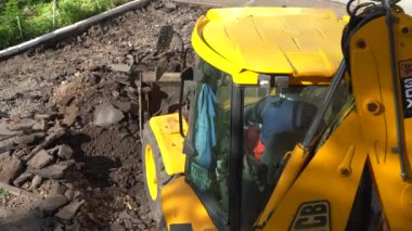 Avrupa, Kiev, Ukrayna - Mayıs 2020: Bir kazıcı traktörü eski asfaltı bir çöp kamyonuna yüklüyor. Eski asfaltı bir çöp kamyonuna yüklüyorum..