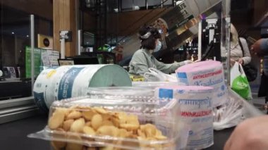 Avrupa, Kiev, Ukrayna - Nisan 2020: Covid-19 Coronavirus salgını sırasında bir süpermarkette tıbbi maske takan bir alıcı yiyecek parasını ödüyor. Süpermarkette nakit masası. Tuvalet kağıdı.