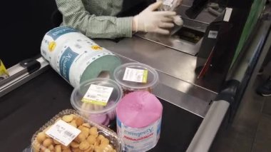 Avrupa, Kiev, Ukrayna - Nisan 2020: Covid-19 Coronavirus salgını sırasında bir süpermarkette tıbbi maske takan bir alıcı yiyecek parasını ödüyor. Süpermarkette nakit masası. Tuvalet kağıdı.