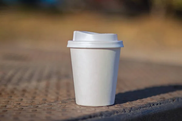 a white paper cup with a lid lies on the city road to the cities of Dnieper