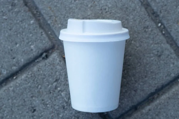 a white paper cup with a lid lies on the city road to the cities of Dnieper