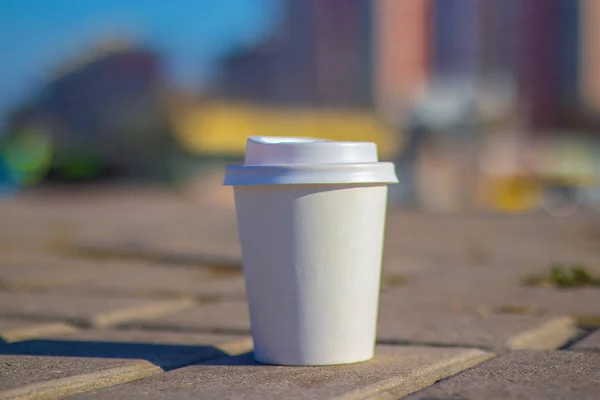 a white paper cup with a lid lies on the city road to the cities of Dnieper