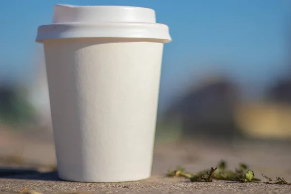 a white paper cup with a lid lies on the city road to the cities of Dnieper