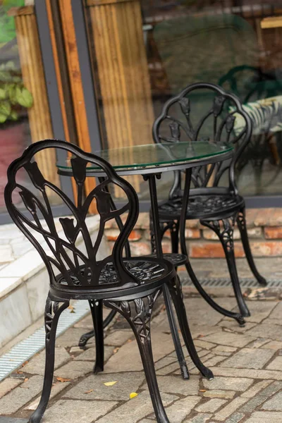 wrought iron chairs and a table near a cafe on the street