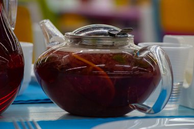 Çayı şeffaf cam çaydanlık farklı otlardan ve meyveleri bir kafede bir masada.