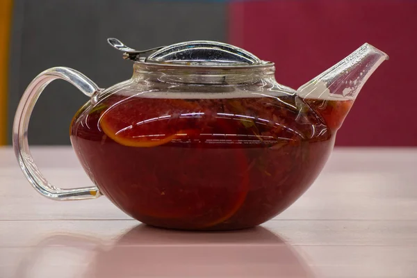 Teiera di vetro trasparente con tè da erbe diverse e frutta su un tavolo in un caffè — Foto Stock