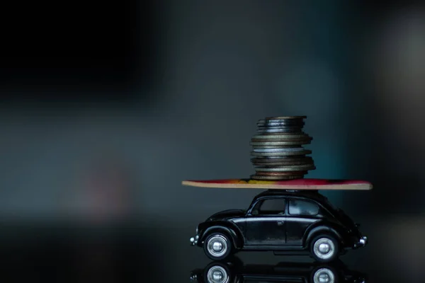 a small toy car with a surfboard on it and a pile of small money is standing on the mirror