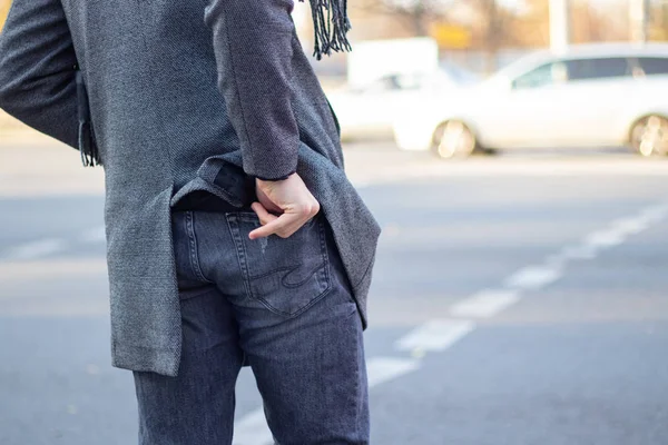 Un hombre toma dinero del bolsillo trasero de sus pantalones vaqueros en la calle en el otoño a las ciudades del Dnieper —  Fotos de Stock