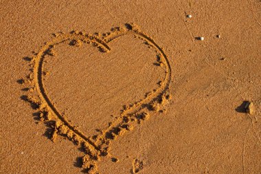 Güneşli bir günde kumda boyanmış bir kalp