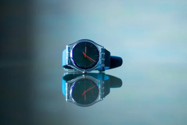 Reloj azul de los hombres se encuentra en la mesa y se refleja en ella —  Fotos de Stock