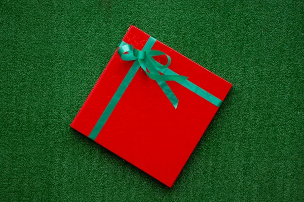 Red gift box on a green background — Stock Photo, Image